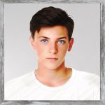 A watercolour picture of a charming young man aged 16. He has neat well groomed brown hair, his eyes are bright blue, and his face has an almost neutral expression although it looks as if he's concentrating. He's wearing a plain white T shirt against a light grey background. The image is labelled NutJob.