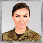 A watercolour painting of a smart, attractive 33 year old female military officer with chestnut coloured eyes, and medium ash brown hair. Her hair is brushed back into a tight bun behind her head. There's a look of concentration on her face and she has a hint of a smile. She's wearing gold stud earrings, dark eye shadow, and pale pink lipstick. Over a dark olive T shirt Commander Crush is wearing MTPs (Multi Terrain Pattern, AKA camouflage).