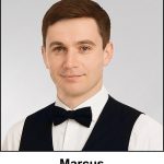 A watercolour painting of of a young man in his early twenties. He has neat well groomed short hair, hazel eyes and a calm smile.Marcus looks like the archetypal waiter, white shirt, black waistcoat and bow tie. He works in the family business, a posh restaurant called Magnum Opus. He plays cricket for Lancaster, and he runs a Irish folk group called The Filthy Peasants (pianist and more).