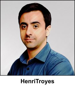 A watercolour painting of a man in his late thirties. He has short, well groomed, dark brown hair and deep brown eyes. His expression is neutral, yet pleasant. He looks like a man who likes to be focussed (on his work probably). He is wearing an open neck, blue denim shirt. The image is labelled HenriTroyes. Although he’s happy if you called him “Henry”, and he’s really happy when you use the French pronunciation “Henri”.