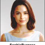 A watercolour painting of a beautiful young 25 year old lady with warm shoulder length light amber brown hair and stunning hazel coloured eyes. She has a pleasant warm smile, and is wearing a simple, pale blue summer dress. The image is labelled SophieBurgess.