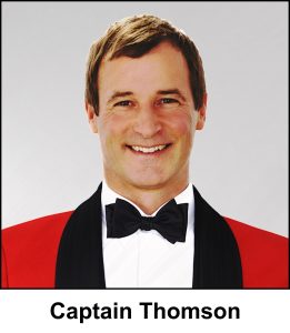 A watercolour painting of a military captain in the amalgated forces of Wolfland, wearing what looks like a bright red Royal Marines No.5 Mess Dress uniform. It has black lapels, and is accompanied by a black bow tie over a bright white wing collar dress shirt. Captain Thomson (aged 58 in this image) has light brown hair, worn a little long for a military man, a welcome smile, and deep brown eyes.