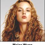 Major Rhona Wynn - A watercolour painting of an attractive 31 year old lady with long, voluminous, honey blonde curly hair (with highlights of both auburn and gold). She has light skin with subtle freckles, soft hazel eyes, structured eyebrows, and full, natural toned lips parted slightly as if about to kiss. She is wearing a floral design top with an adventurous, flamboyant Bohemian look. This is Major Wynn when she is off duty, and making one of her occasional appearances in the Irish folk band called The Filthy Peasants.